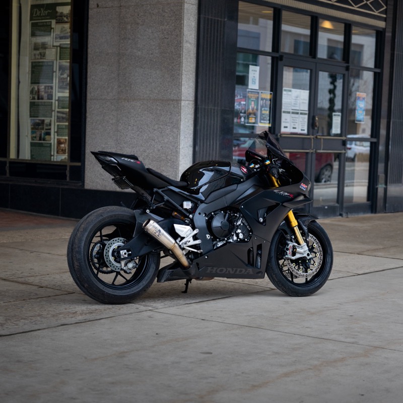 Black Honda CBR1000RR-R Fireblade SP parked by a storefront